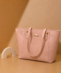 Pink quilted handbag with gold accents on a beige background