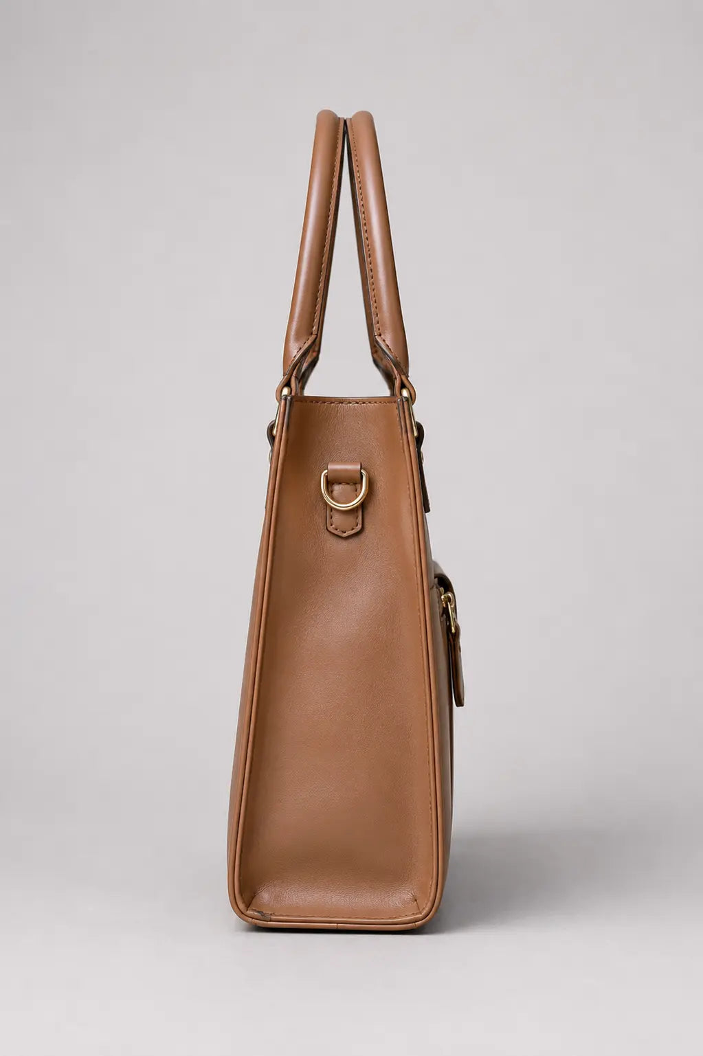 A tan leather tote bag shown from the side against a neutral light gray background.