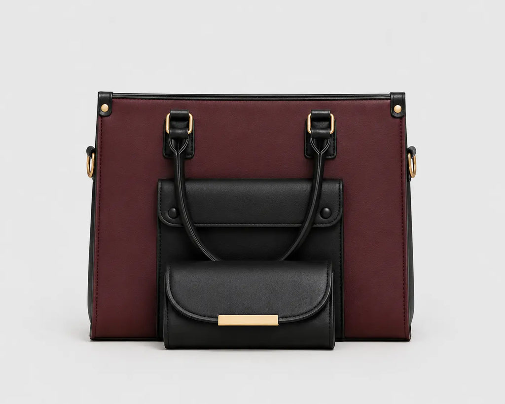 A structured handbag in burgundy and black faux leather, featuring a front flap pocket with a smaller matching black pouch attached in front, set against a plain light gray background.