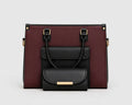 A structured handbag in burgundy and black faux leather, featuring a front flap pocket with a smaller matching black pouch attached in front, set against a plain light gray background.