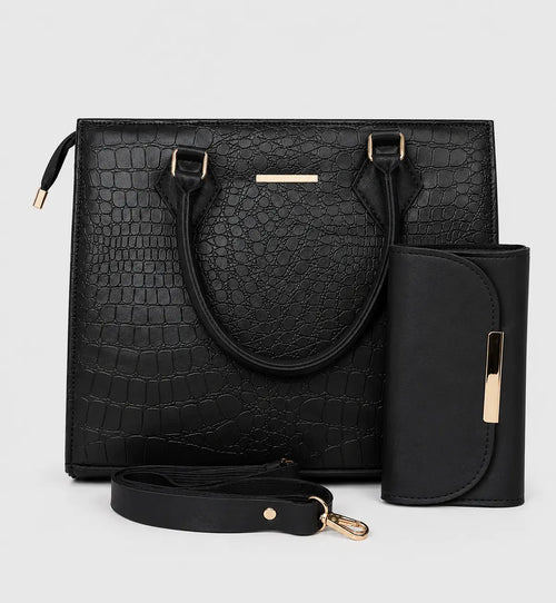 Black crocodile-embossed tote bag with dual top handles, a detachable shoulder strap, a matching vertical wallet, and gold-tone hardware, shown on a light gray background.