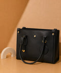 Black leather handbag with gold accents on a brown background