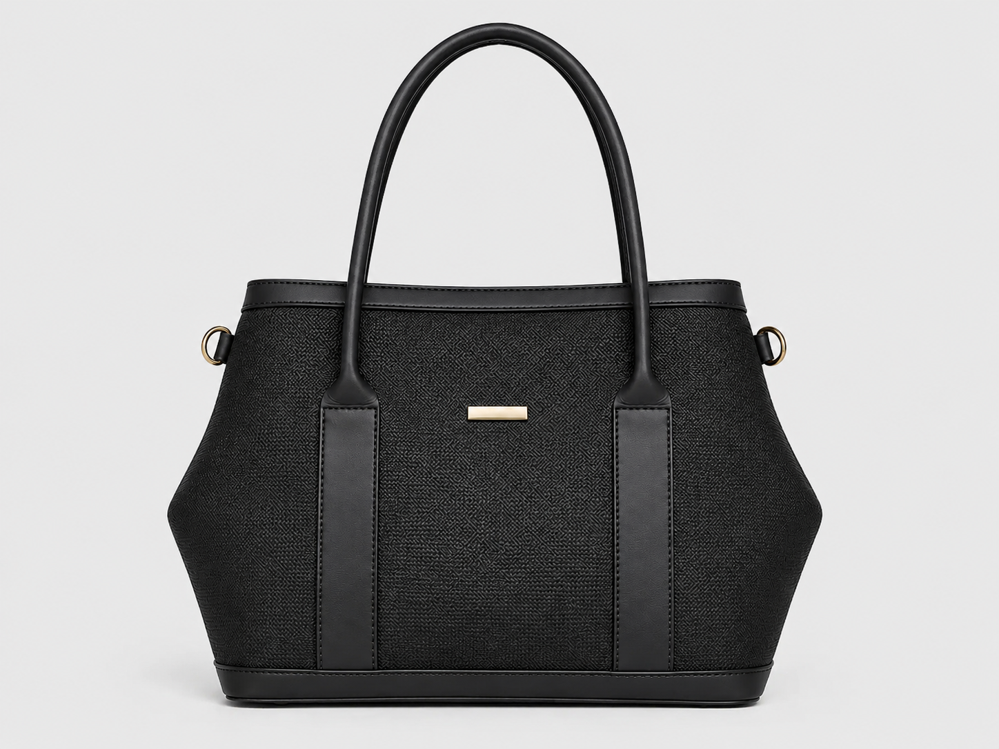 A structured black handbag with a woven texture, dual top handles, vertical leather side panels, and a small gold-tone rectangular logo plaque on the front, shown against a light gray background.