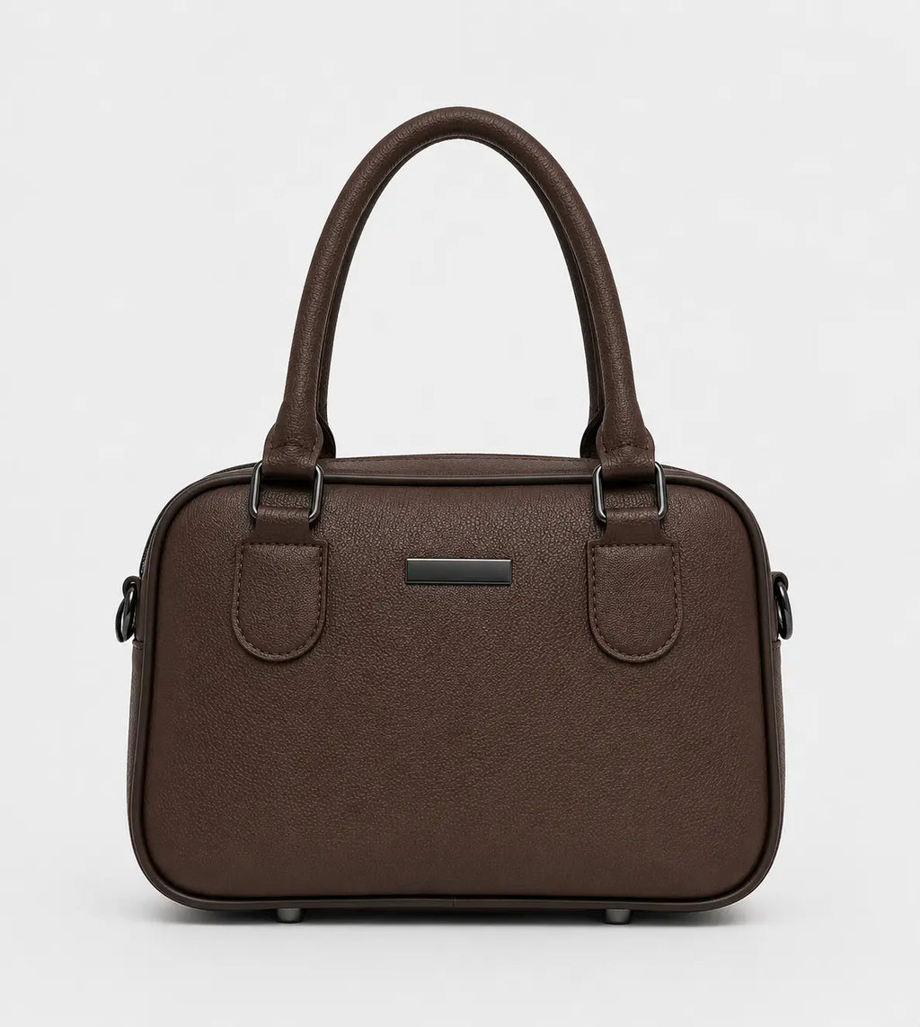 A dark brown textured leather handbag with double top handles, a small rectangular metal plaque on the front, and side hardware, shown against a plain light gray background.