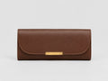 A brown leather long wallet or clutch with a curved flap and a horizontal gold-tone metal bar clasp, shown against a light gray background.
