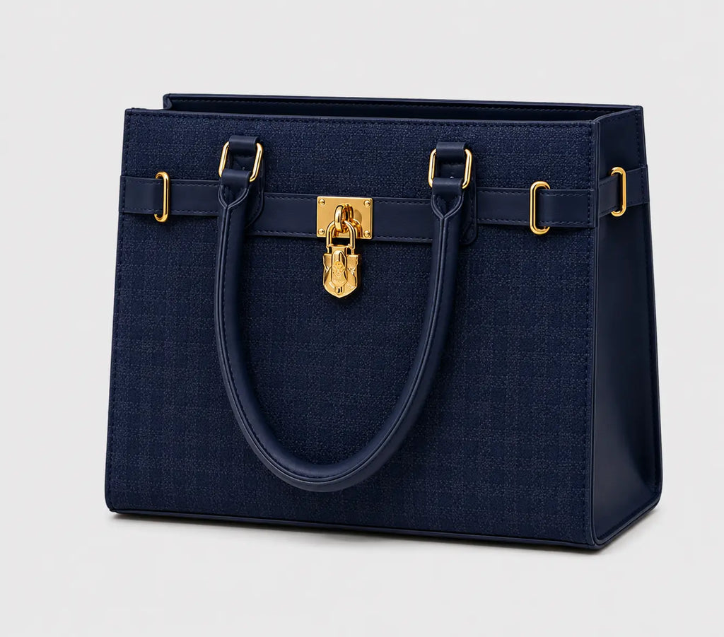 A structured navy blue handbag with a textured woven body, smooth leather handles, and gold-tone hardware, shown on a light gray background.
