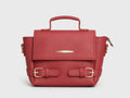 A structured red leather handbag with a top handle, gold-tone buckle straps on the front, and a zippered side pocket, shown against a light gray background.