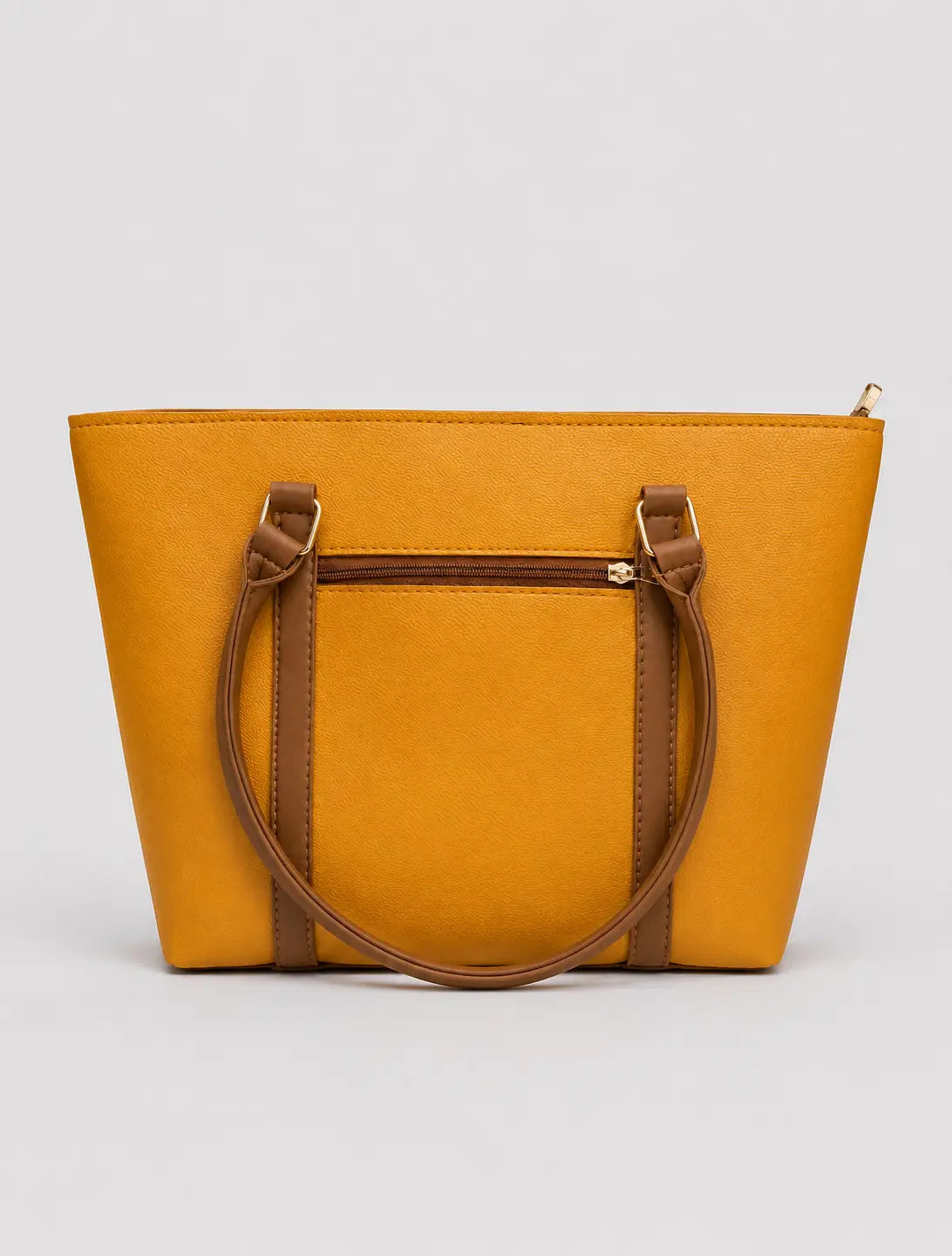 A mustard yellow tote bag with brown faux-leather handles and trim, shown against a neutral light gray background.