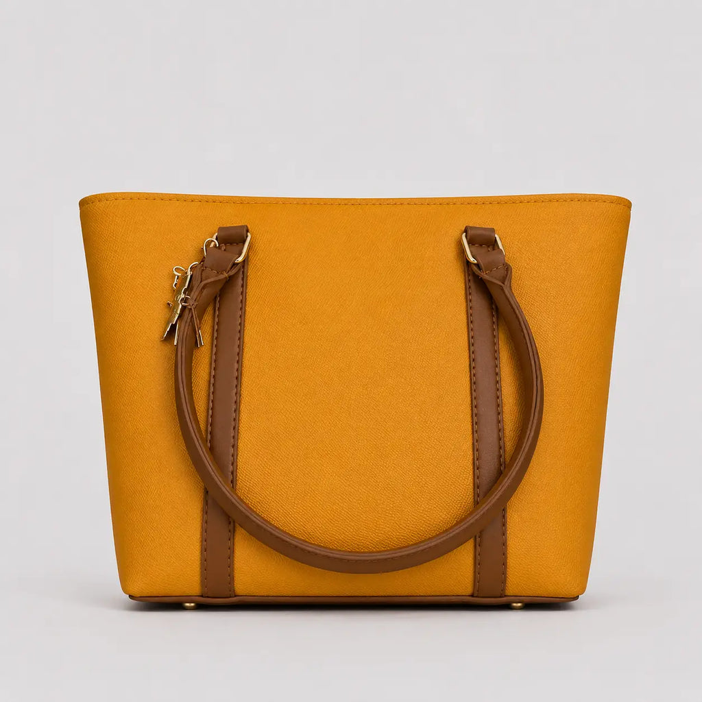 A mustard yellow tote bag with brown leather handles and trim, shown against a neutral light gray background.