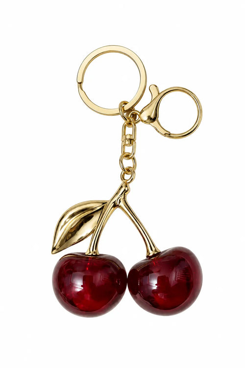 A cherry keychain featuring two glossy red glass cherries attached to gold-tone metal stems, rings, and a lobster clasp, shown on a plain white background.