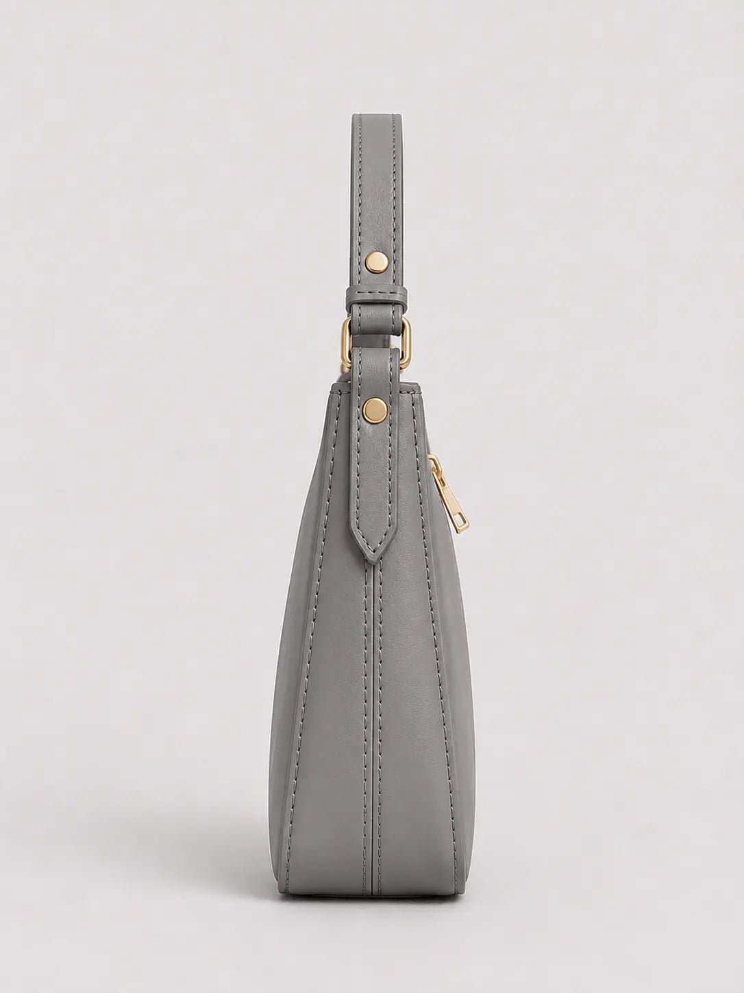 A gray leather shoulder bag shown from the side, featuring a slim strap, gold-tone hardware, and a zippered closure, set against a light gray background.