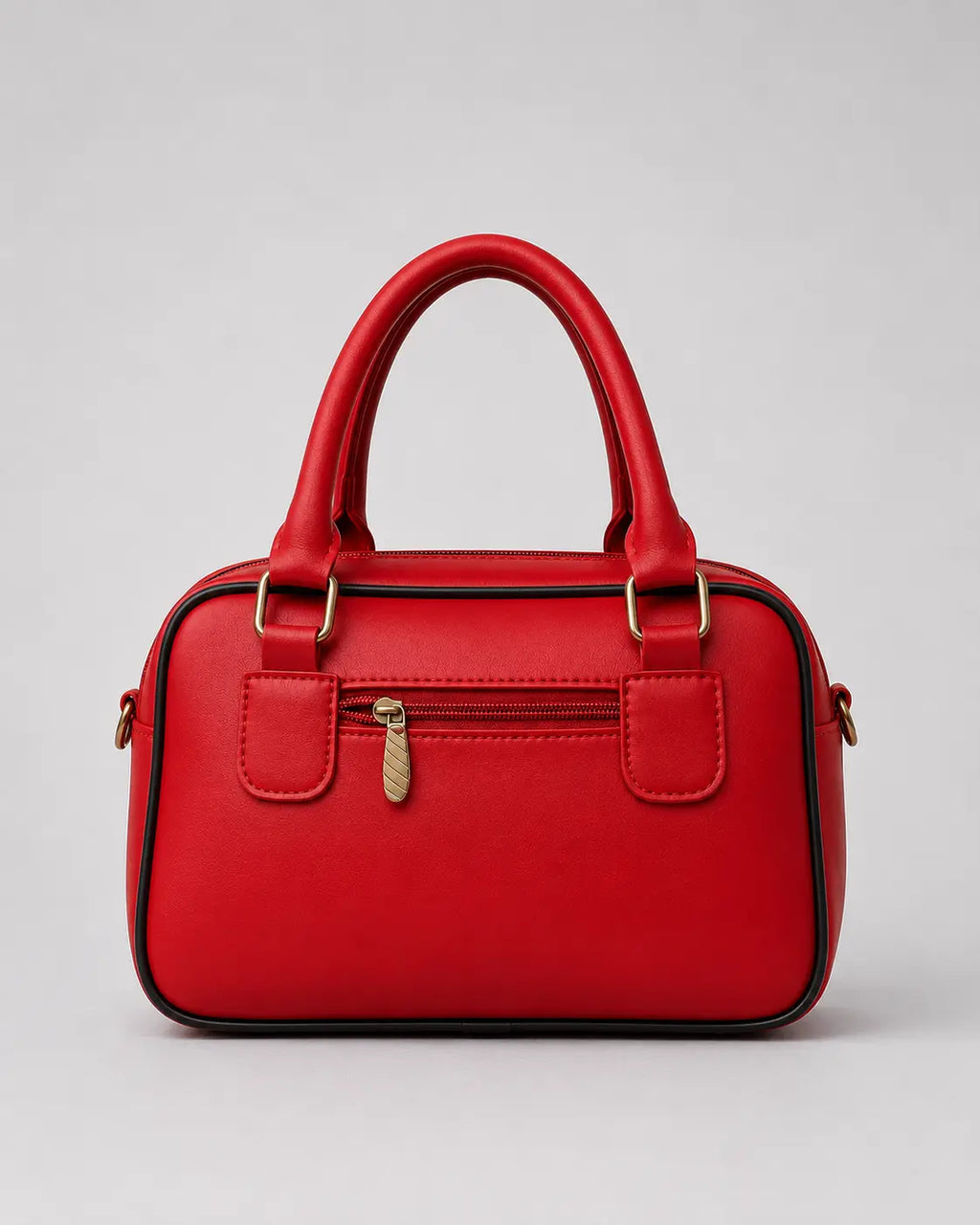 A bright red faux leather handbag with double top handles, a front zippered pocket with a gold-tone zipper pull, and gold-tone hardware, shown against a neutral gray background.