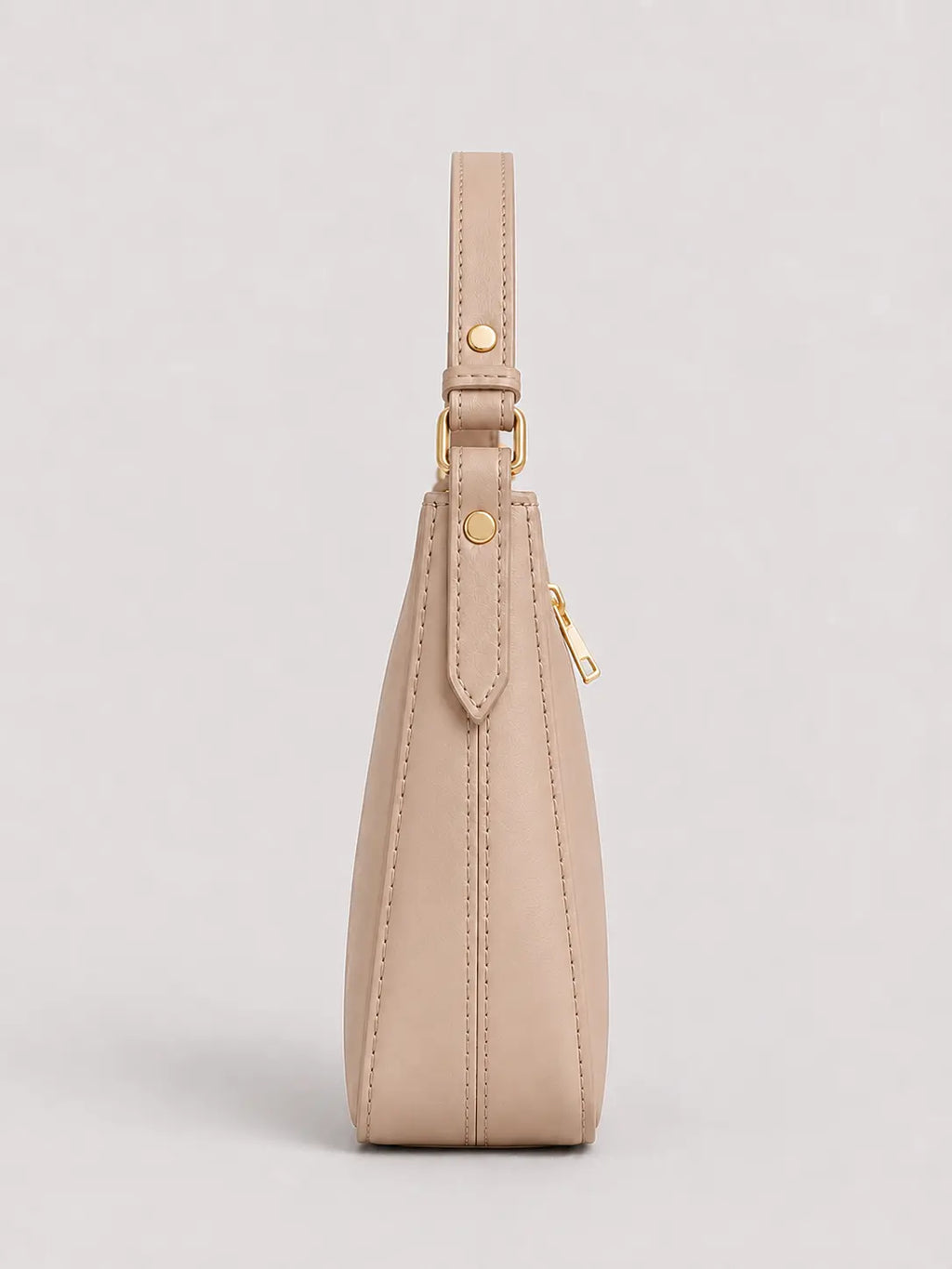 A side profile view of a beige leather shoulder bag with gold-tone hardware, shown against a neutral light gray background.