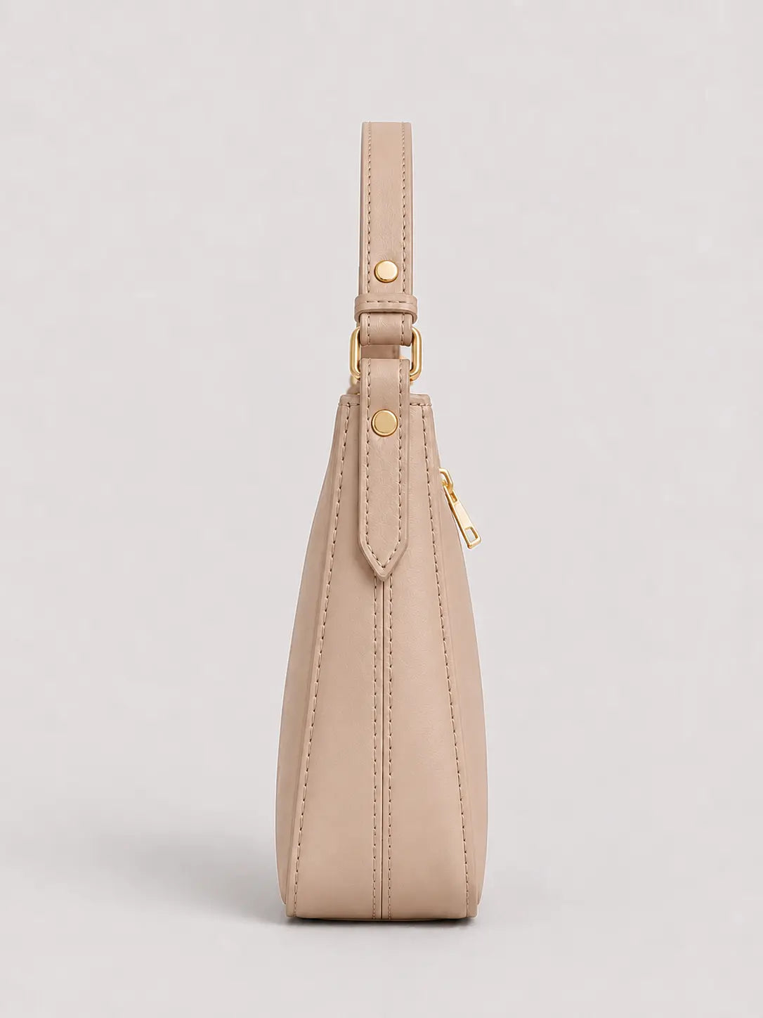 A side profile view of a beige leather shoulder bag with gold-tone hardware, shown against a neutral light gray background.